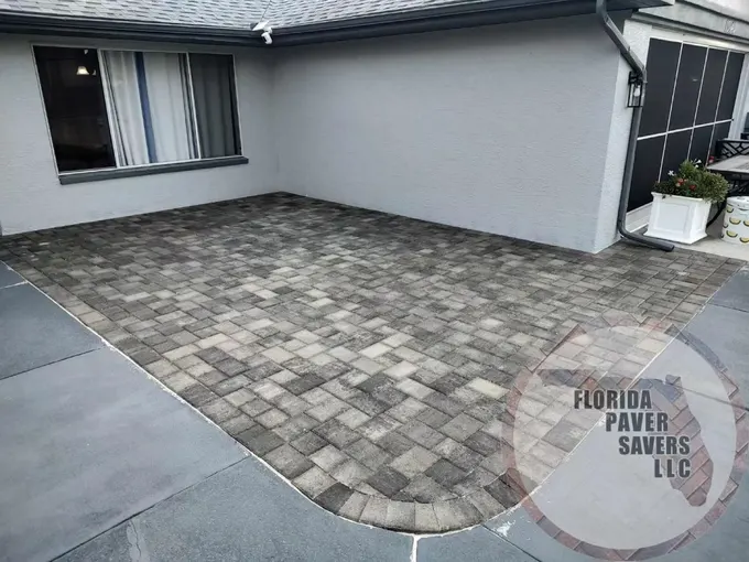 Gray paver patio with a rounded corner beside a screened lanai