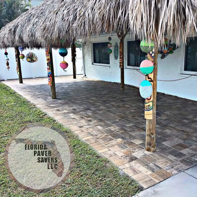 Paver patio beneath a thatched outdoor shelter beside a home