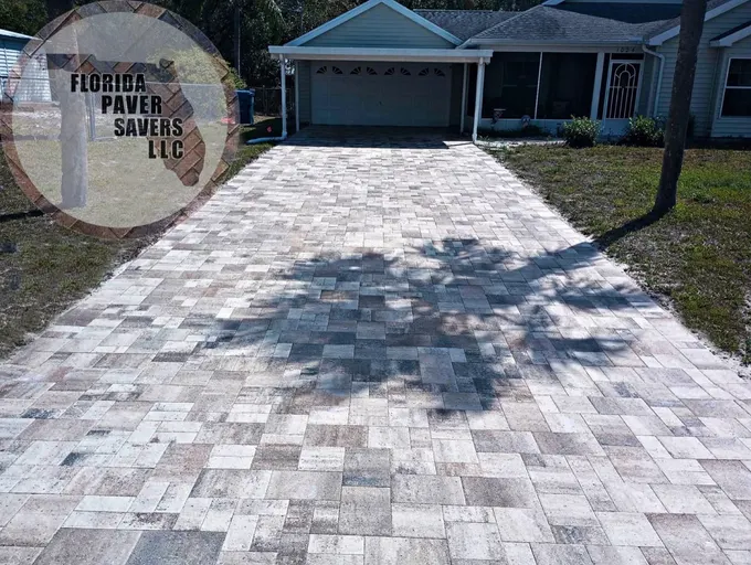 Light gray driveway pavers leading to a dark garage door