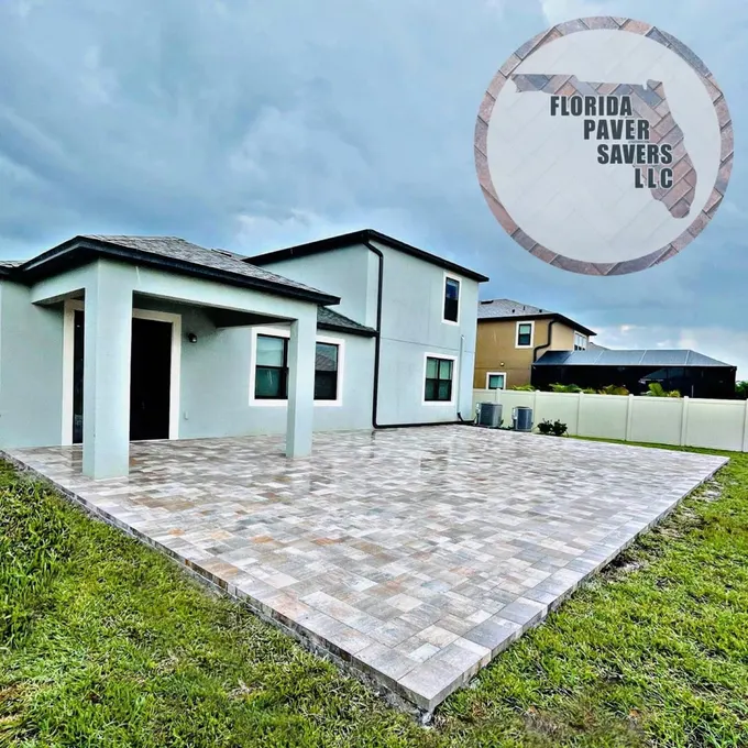 Large light gray paver patio at the rear of a two-story home