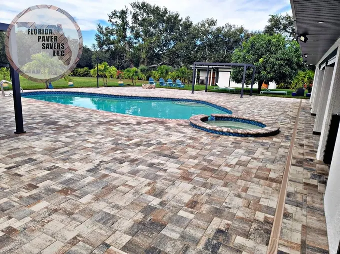Large multicolor paver deck beside a swimming pool and circular spa