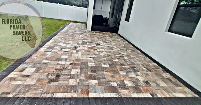Multicolor paver patio beside a house and screened enclosure