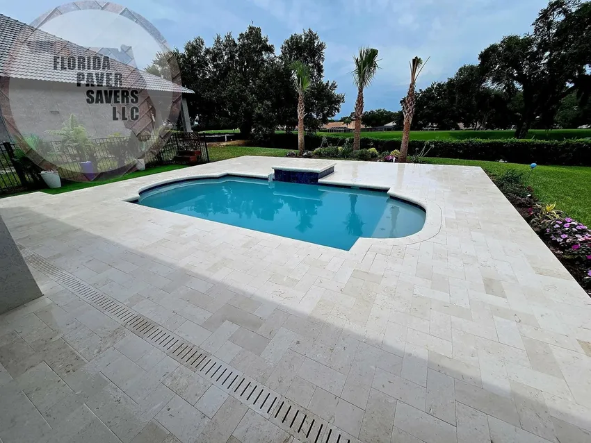 Light travertine pool deck around a swimming pool and raised spa