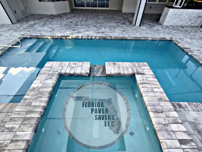Gray paver deck and raised spa coping around a rectangular swimming pool