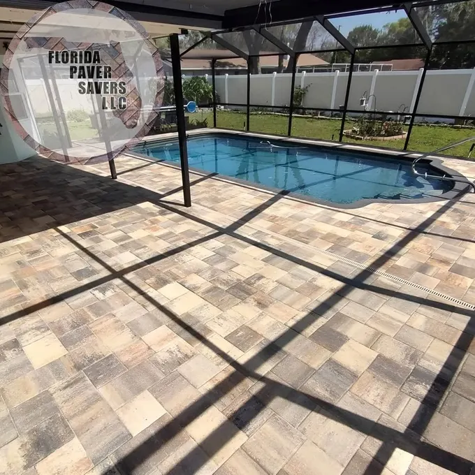 Tan and gray paver deck around a screened swimming pool