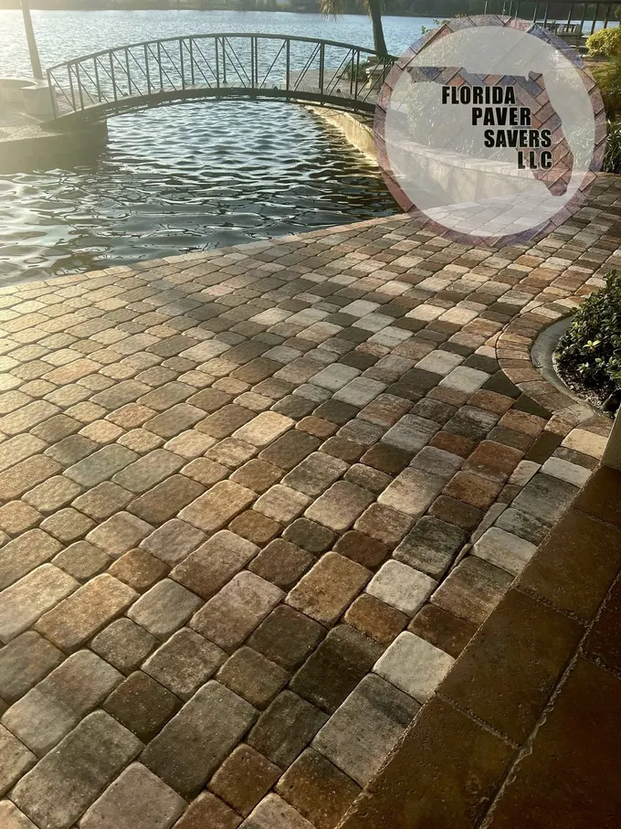 Waterfront paver patio beside a curved footbridge