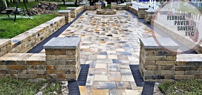 Paver courtyard enclosed by low stone walls and capped entrance pillars