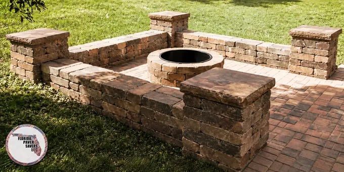 Circular stone fire pit with seating walls and brown capped columns on a paver patio