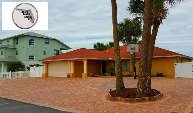 Wide view of a red paver driveway curving around a palm tree planting bed