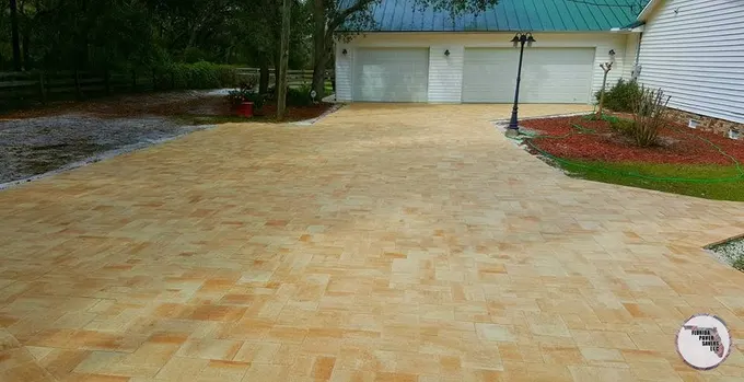 Broad tan paver driveway in front of a white detached garage